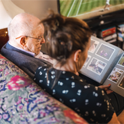 Older man and woman looking at a photo album on a sofa